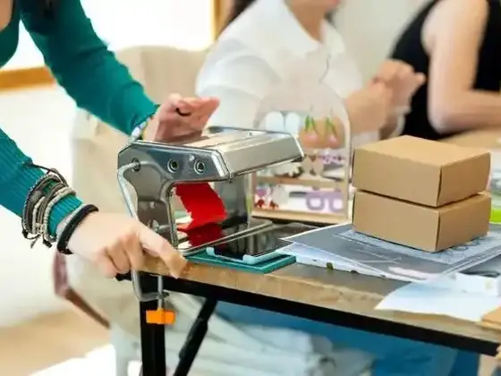 Team member sealing product samples with packaging equipment on a workshop table
